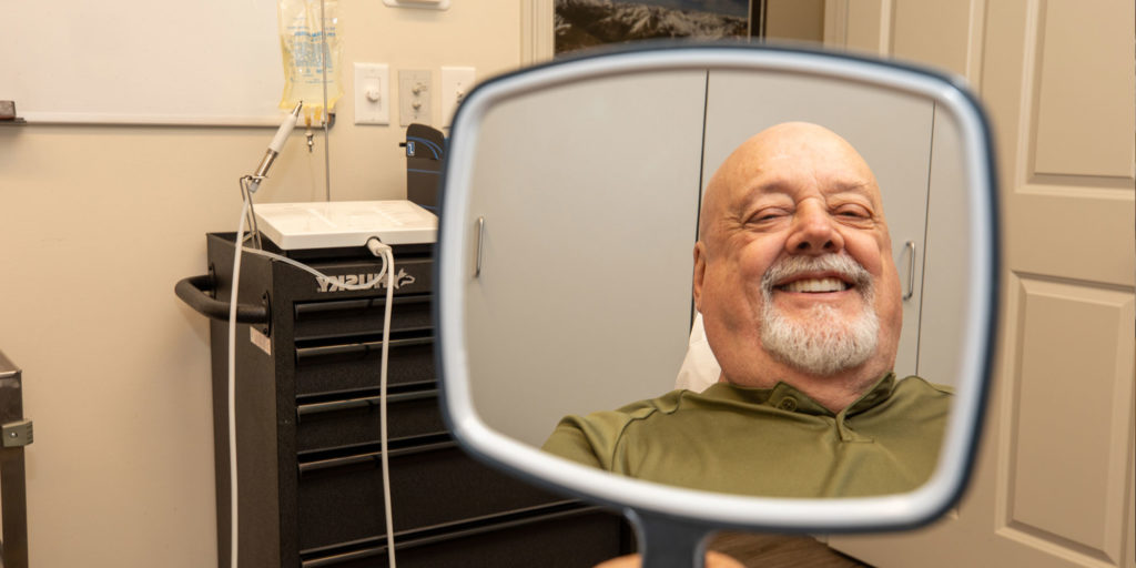 tharp, klaus, and kelly patient admires dental veneers