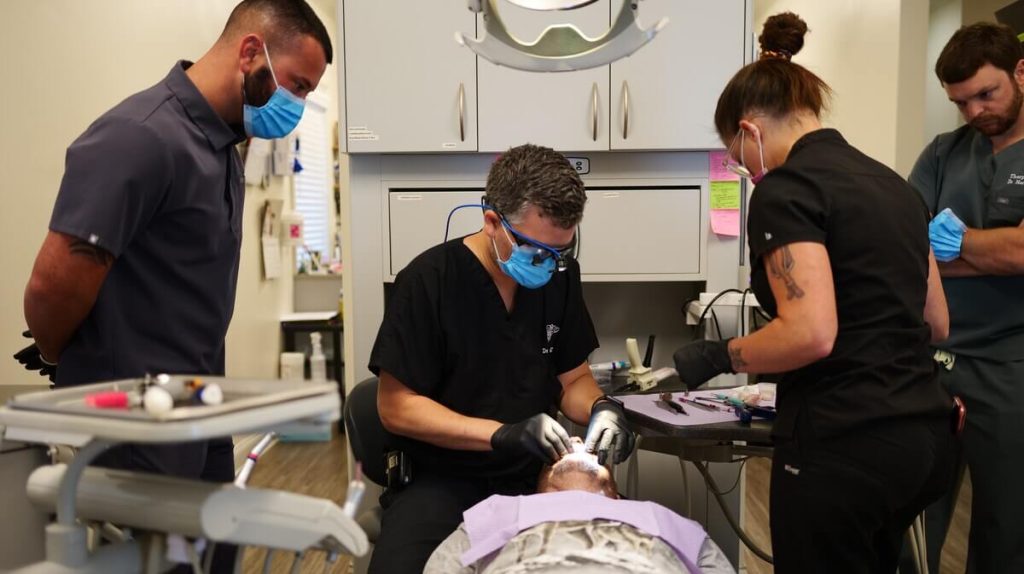 dentists complete dental implant procedure on patient